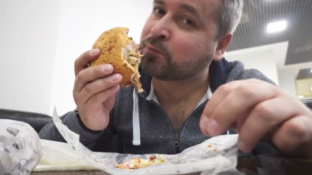 飢えた男を食べる大きなハンバーガー ファーストフード カフェで — ストック動画