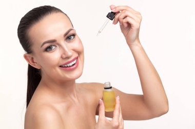 Genç kadının yüzüne pipet ile uygulayarak Kozmetik yağı closeup çekim. Güzellik terapi kavramı. 
