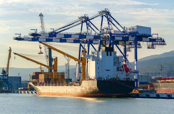 Container ship is loading in a port, evening light