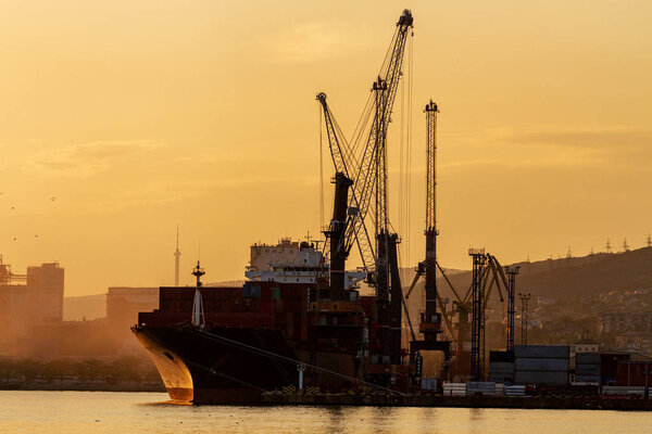 Container ship is loading in a port, evening light, dusk