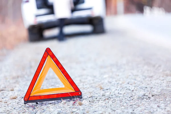 Closeup shot of warning red triangle sign, broken car and girl — Stock Photo, Image
