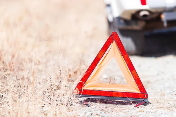 Nahaufnahme des roten Not-Stopp-Schildes und des kaputten weißen Autos am Straßenrand — Stockfoto