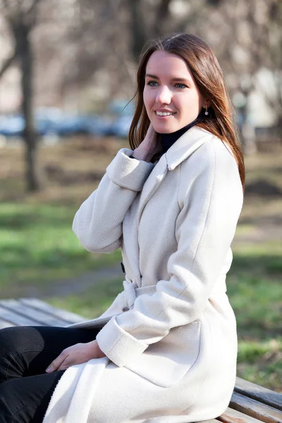 Pretty girl sitting on a bench in a city park — Stock Photo, Image