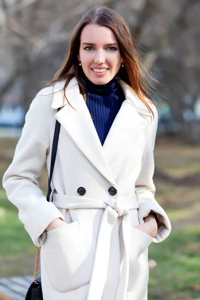 Chica bonita con abrigo blanco posando en un parque de la ciudad — Foto de Stock