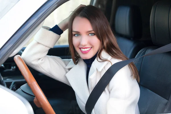 Pretty kvinna förare ler till dig från hennes bil — Stockfoto