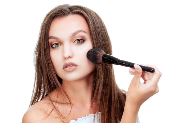 Closeup shot of young girl who applies powder on her face using makeup brush, isolated on white background — Stock Photo, Image