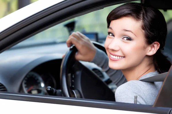 Lycklig ägare till en ny bil. Pretty kvinna förare leende till dig från hennes bil — Stockfoto