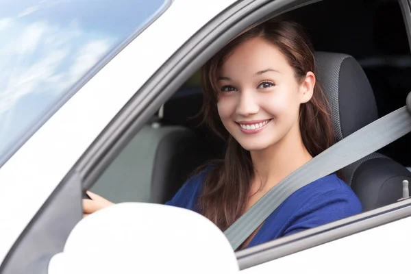 Feliz dono de um carro novo. Bonita mulher motorista sorrindo para você de seu automóvel — Fotografia de Stock