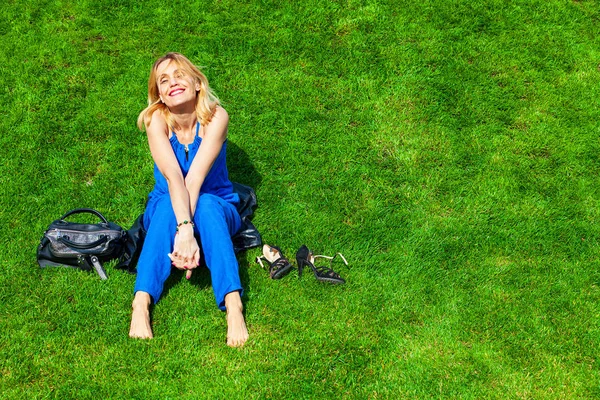 快乐的女人坐在绿草地上 — 图库照片