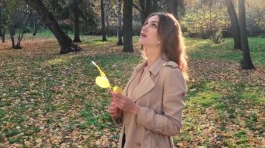 Güz parkında yapraklı güzel bir kadın.