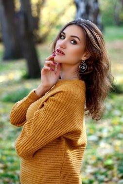 Güz parkında ya da ormanda poz veren güzel bir kadın.