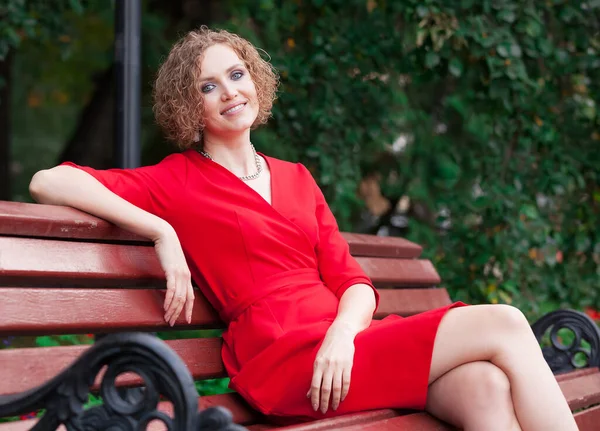 Happy Woman Red Dress Sitting Bench Park Smiling You — Stock Photo, Image