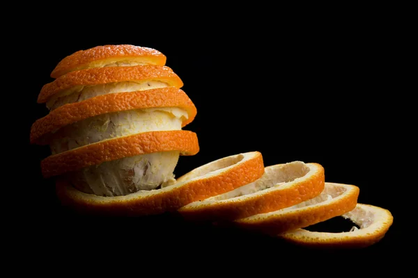 Peeled orange on black background. Removed peel formed a spiral tape. Looks like dancing orange with the ribbon. Side view.