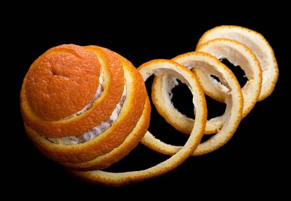 在黑色背景上去皮橙色 去掉的果皮形成了螺旋胶带 看起来像是用丝带跳舞橙色的 顶部视图 — 图库照片