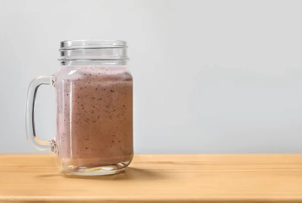 Batido de bagas em um pote de pedreiro em uma placa de corte de madeira . — Fotografia de Stock