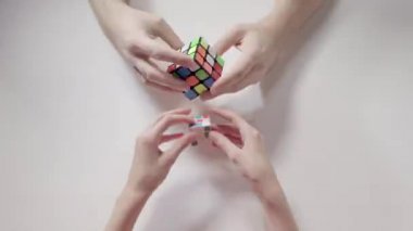 Adamın ve çocuğun elleri Rubik küpü çözme bulmaca. Bulmaca küp, puzzle oyunu, en çok satan oyuncak. Adamın ve çocuğun elleri portre. Bölüm 02. Hız yukarıya.