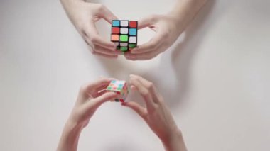 Adamın ve çocuğun elleri Rubik küpü çözme bulmaca. Adamın rubik küpü çözülmüştür. Bulmaca küp, puzzle oyunu, en çok satan oyuncak. Adamın ve çocuğun elleri portre. Bölüm 01. Hız yukarıya.