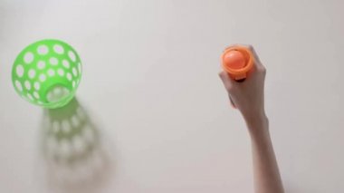 Çocuğun elleri ile shooter oynayan turuncu topu ve yeşil sepet ile oyuncak. Çocuğun closeup eller. Bölüm 01.