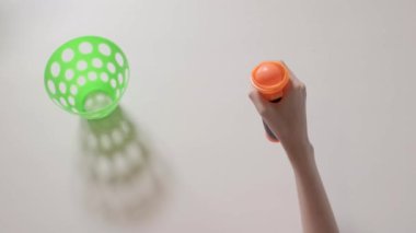 Çocuğun elleri ile shooter oynayan turuncu topu ve yeşil sepet ile oyuncak. Çocuğun closeup eller. Bölüm 02.