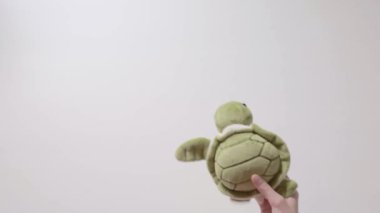 Çocuk bir yumuşak yeşil kaplumbağa oyuncakla oynar. Part_06. Çocuğun el oyuncak closeup ile.