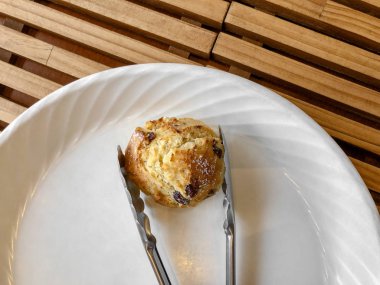 Ahşap bir masa üzerinde beyaz bir bitki üzerinde üzümlü çörek. IPhone foto.