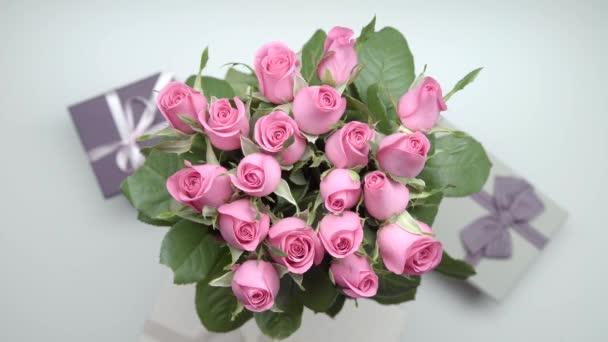 女性の手はピンクのバラの花束を検索し テーブルの上を提示します — ストック動画