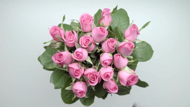 Frauenhände legten einen Strauß pinkfarbener Rosen und zwei Geschenke auf den Tisch. 21