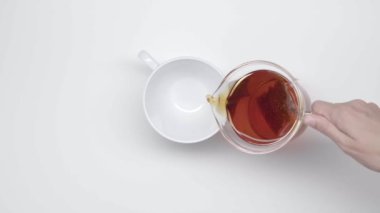 Eller bir çay cam çaydanlık çay poşeti ile gelen Çin bardak beyaz zemin üzerine dökün. Ağır çekim. Çay töreni. Bölüm 29.