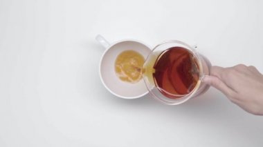 Eller Çin çay poşeti ısıtıcısı cam bardaktan bir çay beyaz zemin üzerine dökün. Ağır çekim. Çay töreni. Bölüm 31.