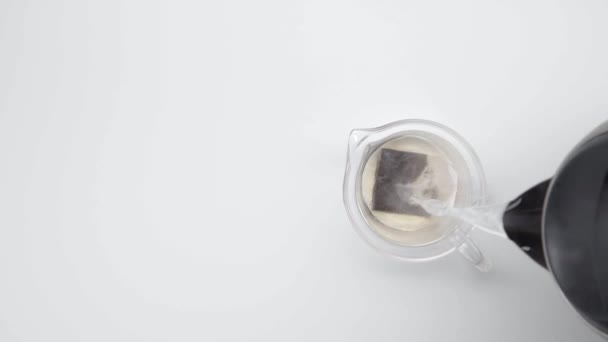 Versare Acqua Calda Nel Bollitore Vetro Con Bustina Sfondo Bianco — Video Stock