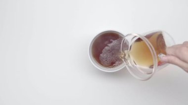 Eller bir çay cam çaydanlık üzerinden Çin Kupası beyaz zemin üzerine dökün. Ağır çekim. Çay töreni. Bölüm 46.