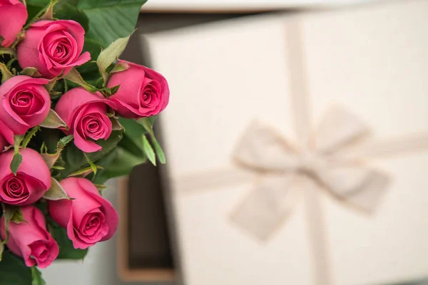 Bouquet of pink roses with gifts on the table.
