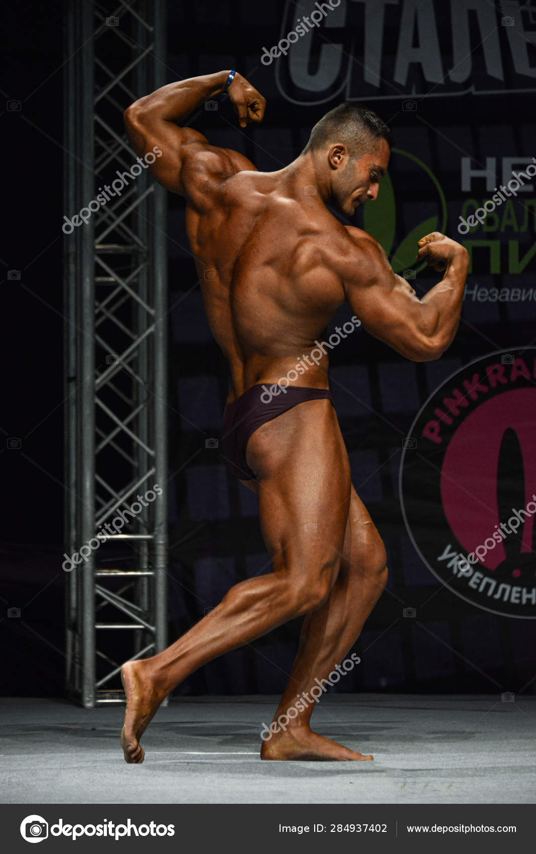 Athlete in back double biceps pose. Bodybuilder showing muscles on studio  background Stock Photo by ©Bossa_Nova 177340232