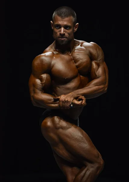 Fisiculturista masculino flexiona seus músculos — Fotografia de Stock