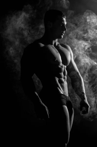 Fitness male model in studio with a smoke