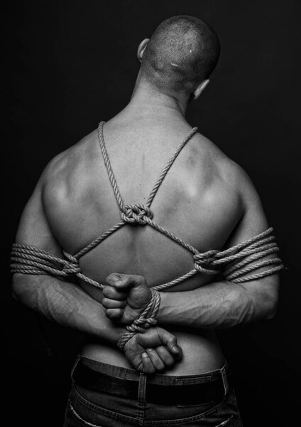 Muscled male model roped in traditional japanesse shibari