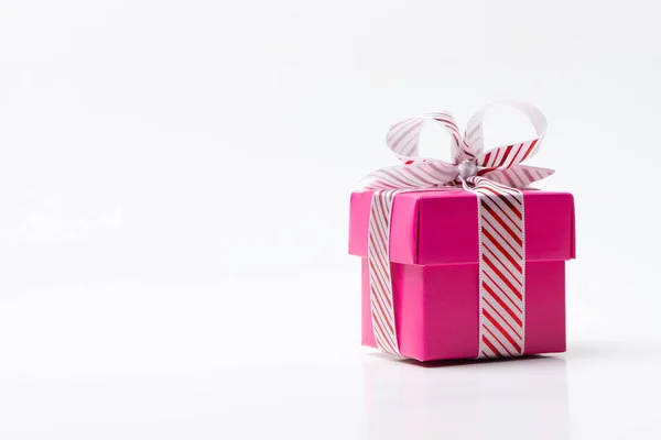 Pink gift box tied with white red stripe ribbon — Stock Photo, Image