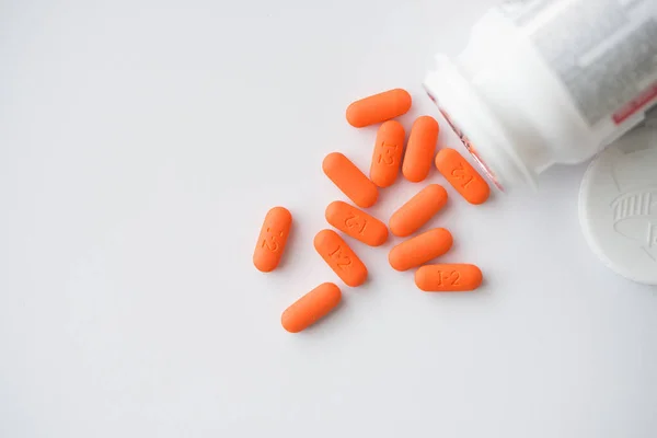 Orange pills cascading out of white bottle view from top — Stock Photo, Image