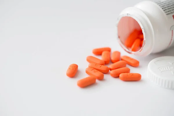 Pilules orange en cascade hors de la bouteille blanche — Photo