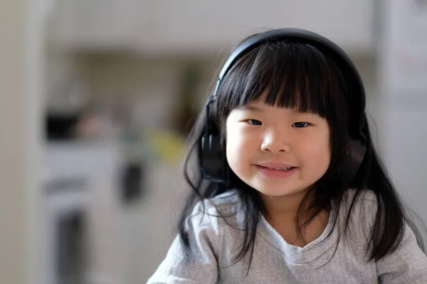 Ένα νεαρό κορίτσι της Ασίας απολαμβάνει να ακούτε μουσική στο ακουστικό της — Φωτογραφία Αρχείου
