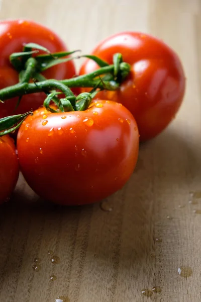 Panículas de tomates en una tabla de cortar de madera — Foto de Stock