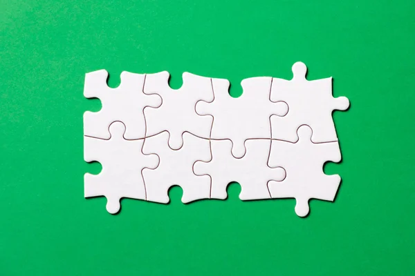 Eight pieces white jigsaw puzzle on green background for business presentation — Stock Photo, Image