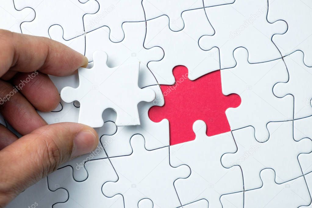 Hand putting the last piece of white puzzle for business concept or content background