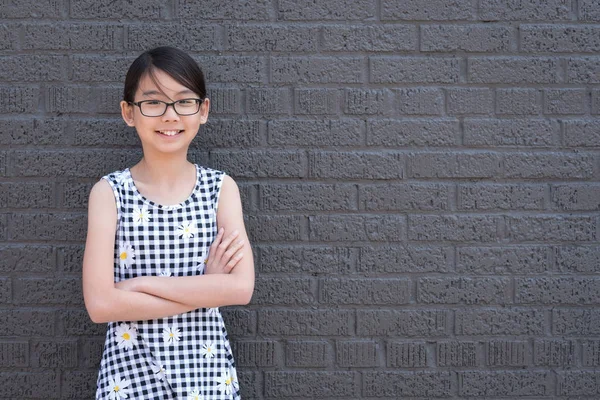 Portrait of young Asian girl against black brick wall — Stock Photo, Image