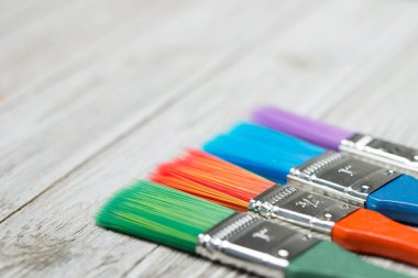 Gri ahşap arka planda çok renkli boya fırçaları