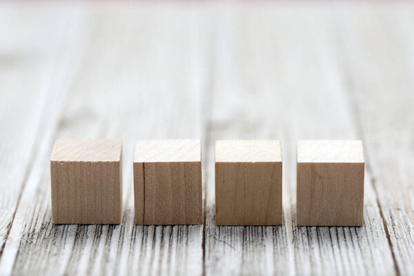 Four wooden toy cubes on grey wooden background