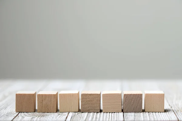 Zeven houten speelgoed kubussen op grijze houten achtergrond — Stockfoto