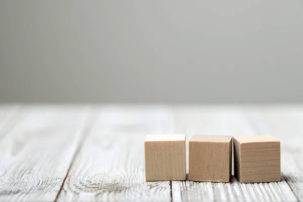 Drie houten speelgoed kubussen op grijze houten achtergrond — Stockfoto