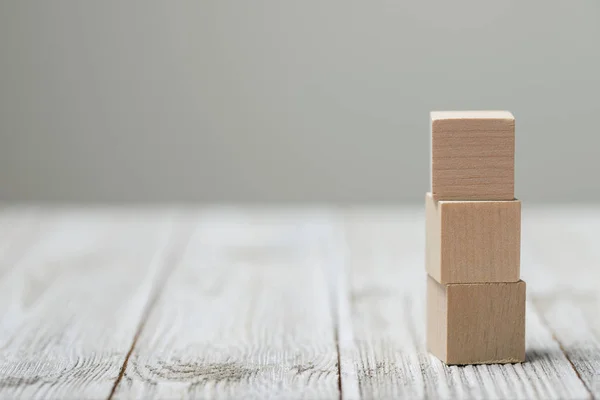 Three wooden toy cubes on grey wooden background