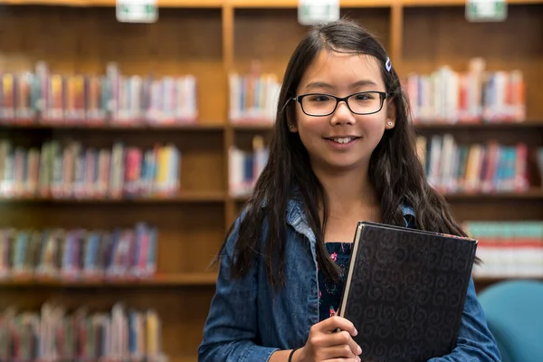 Dospívající dívka s brýlemi ve školní knihovně — Stock fotografie